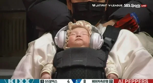 배구 경기장에서 헤드폰 끼고 수면중인 아기 관객.jpg